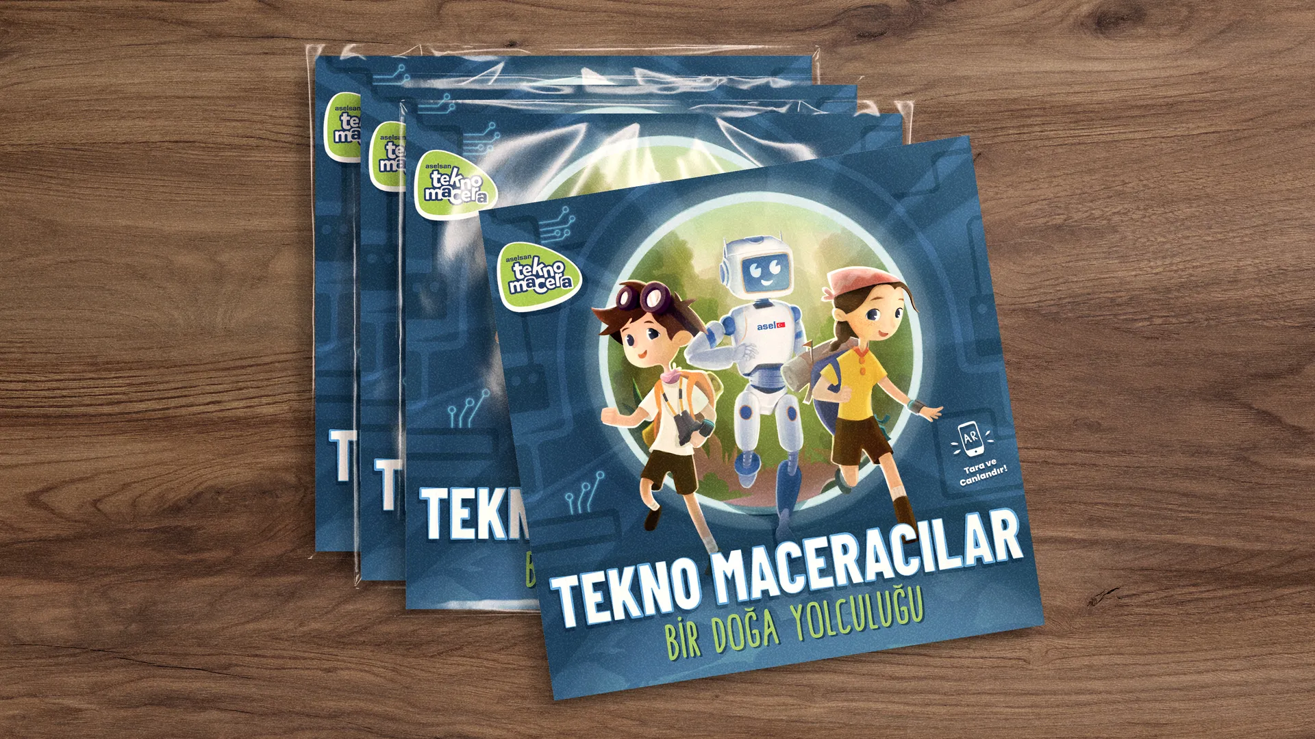 Tekno Maceracilar - copies of the children’s book fanned out on a wooden table, the cover showing two young explorers and a friendly robot