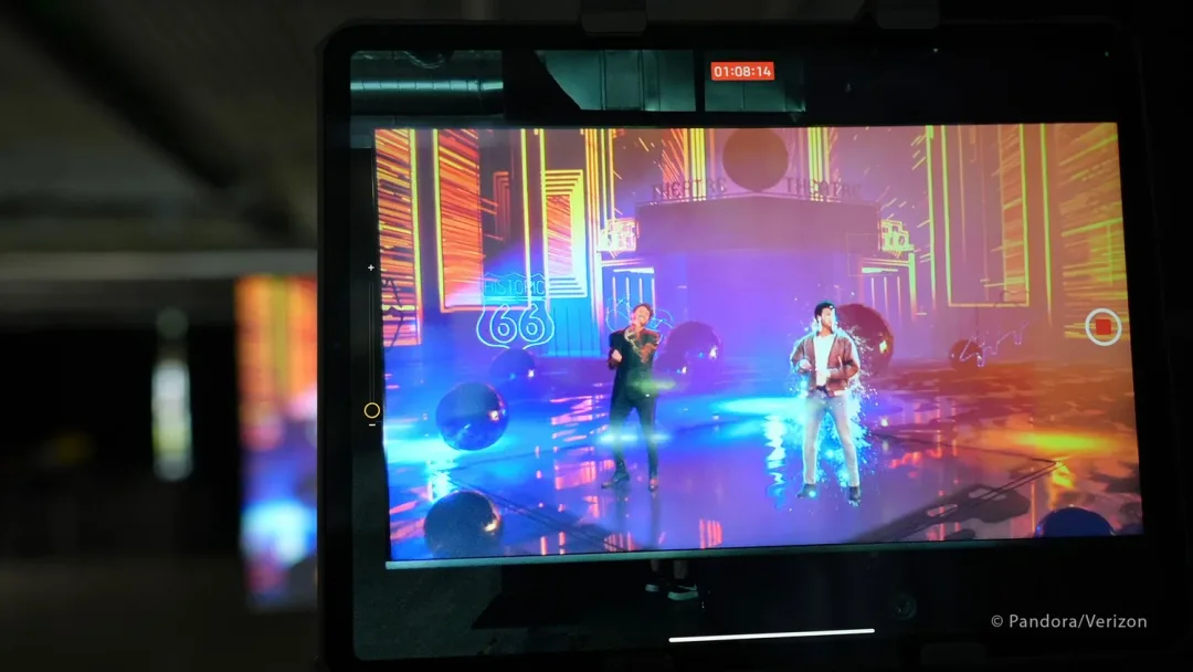 A monitor on set showing the live composite of two performers inside a neon Route 66 virtual environment